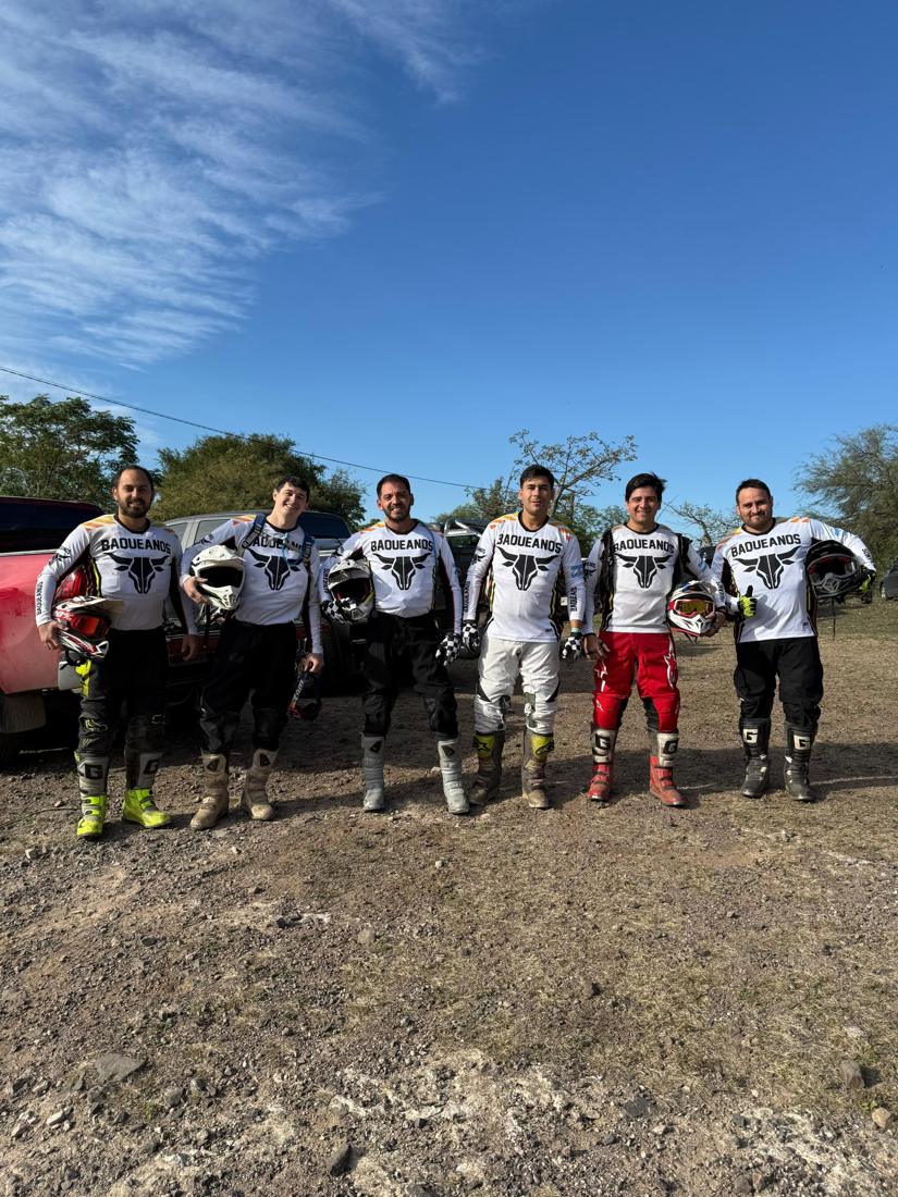 Seis pilotos de BAQUEANOS con camisetas blancas y cascos en la mano